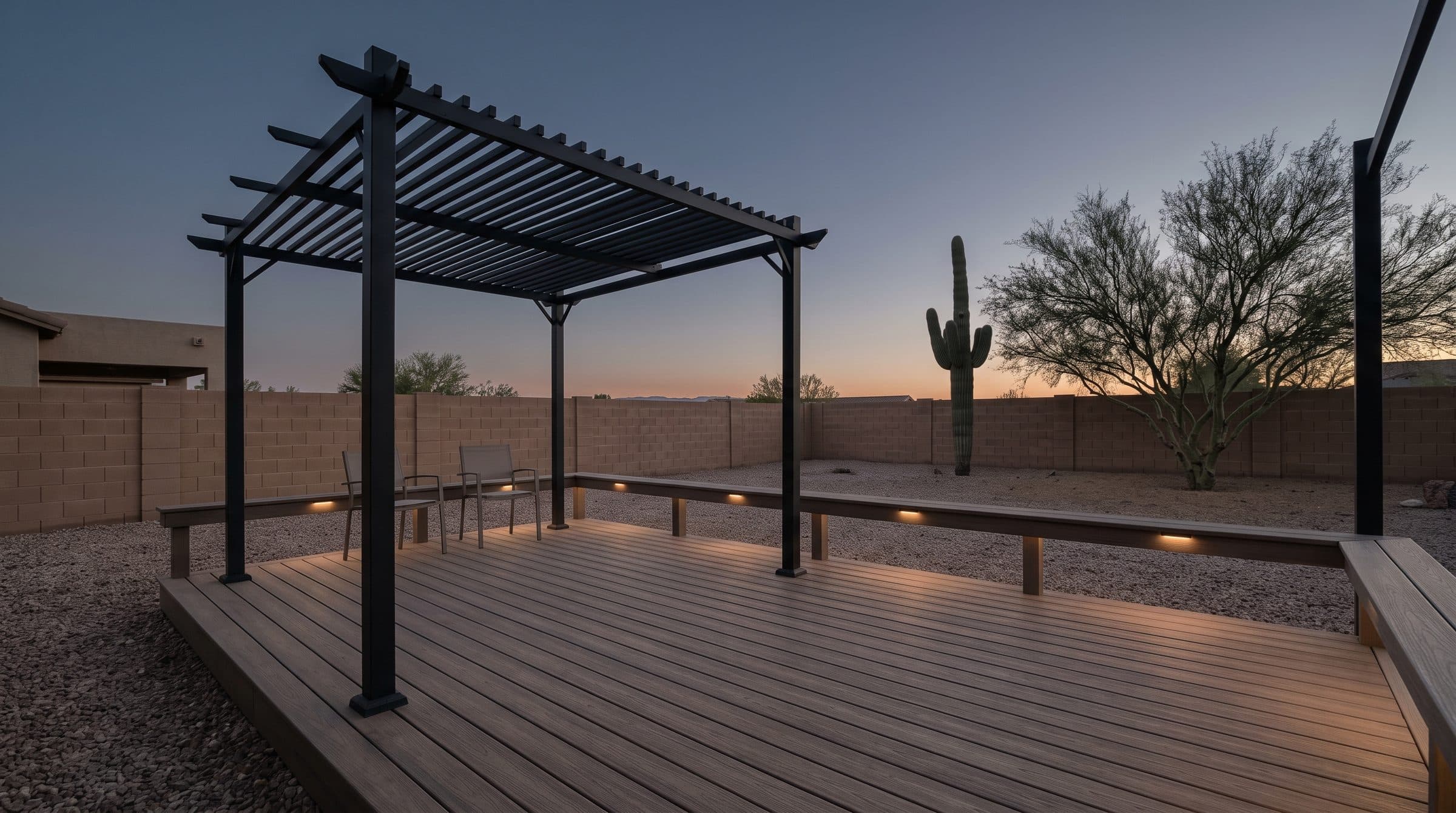 Composite deck with a black steel pergola at dusk, gravel yard and saguaro beyond